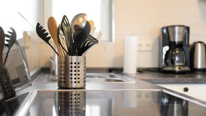 A kitchen with stainless steel appliances, a coffee maker, and utensils in a holder.