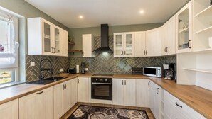 Una cocina moderna con armarios blancos, una campana extractora negra, un microondas y una encimera de madera.