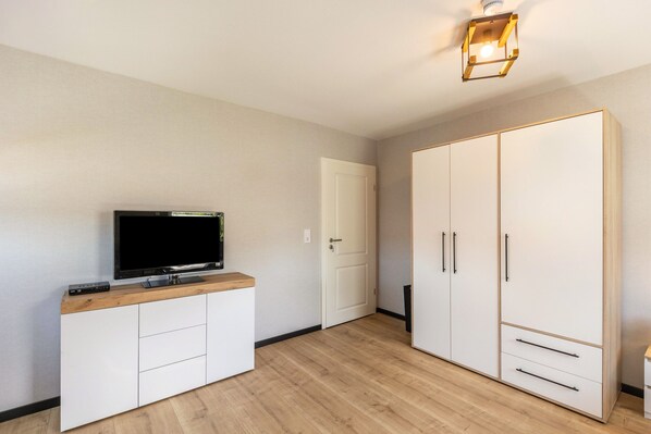 Una habitación con televisión sobre un mueble de madera, un armario y una puerta.