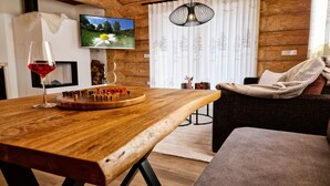 A wooden table with a chessboard, a wine glass, and a television displaying a nature scene.