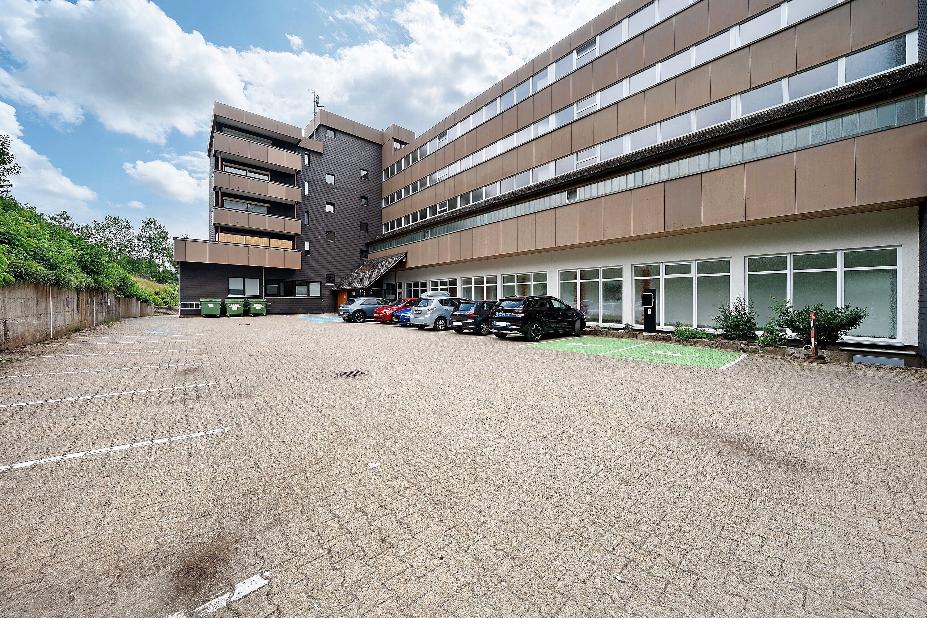A multi-story building with a parking lot in front.