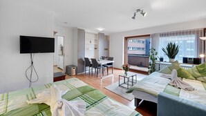 A hotel room with a bed, a TV, a desk, and a dining area. - Apartment Schanzenblick with Sauna & Pool in the Black Forest (Schönwald im Schwarzwald)