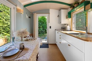 Eine Küche mit Essbereich, einem Fenster mit Blick auf Grünflächen und einer Tür, die nach draußen führt.