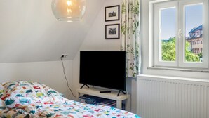 Ein Schlafzimmer mit einem Bett, einem Fernseher auf einem Schrank, einem Fenster mit Blick und einer Hängelampe.