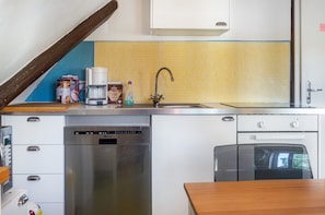 Una cocina pequeña equipada con lavavajillas, cafetera y lavabo.