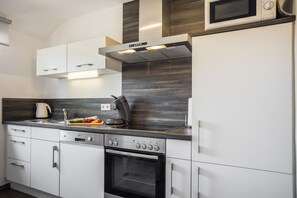 Een moderne keuken met witte kasten, een roestvrijstalen afzuigkap en een ingebouwde oven.