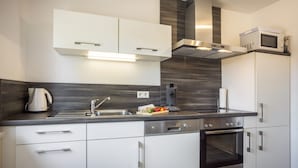 Une cuisine moderne avec des meubles blancs, des appareils en acier inoxydable et un four encastré.