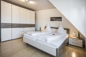Een moderne slaapkamer met een groot bed, een nachtkastje, een kledingkast en een stadsgezichtschilderij aan de muur.