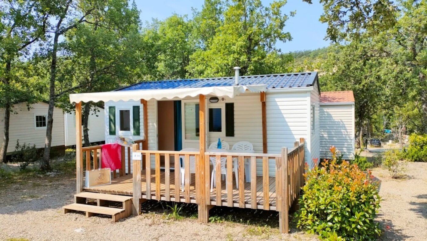 Une petite maison mobile d’un seul étage, dotée d’un porche et d’une terrasse couverte.