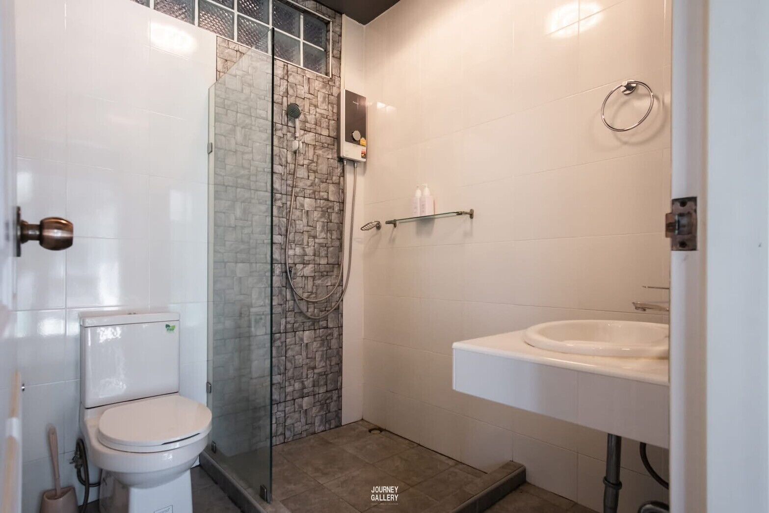 A bathroom with a glass shower enclosure, a toilet, and a sink.
