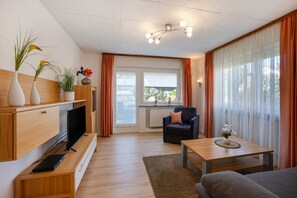 Een moderne woonkamer met een flatscreen televisie, een bank, een salontafel en een open haard.