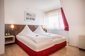 A double bed with white linens, a nightstand with a vase of green plants, and a framed picture on the wall. - Apartment 'Bodensee' with Garden, Balcony and Wi-Fi (Friedrichshafen)