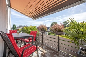 An outdoor patio with a table and chairs, a pergola, and potted plants. - Apartment 'Bodensee' with Garden, Balcony and Wi-Fi (Friedrichshafen)