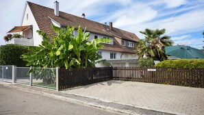 A residential property with a paved driveway, a wooden fence, and a sign indicating a parking area. - Apartment 'Bodensee' with Garden, Balcony and Wi-Fi (Friedrichshafen)