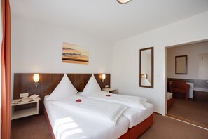 Une chambre d’hôtel avec un lit, des tables de chevet, un bureau, une chaise et un tableau au mur.