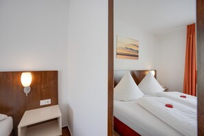 Ein Hotelzimmer mit Bett, Nachttisch, Lampe und einem Gemälde an der Wand.