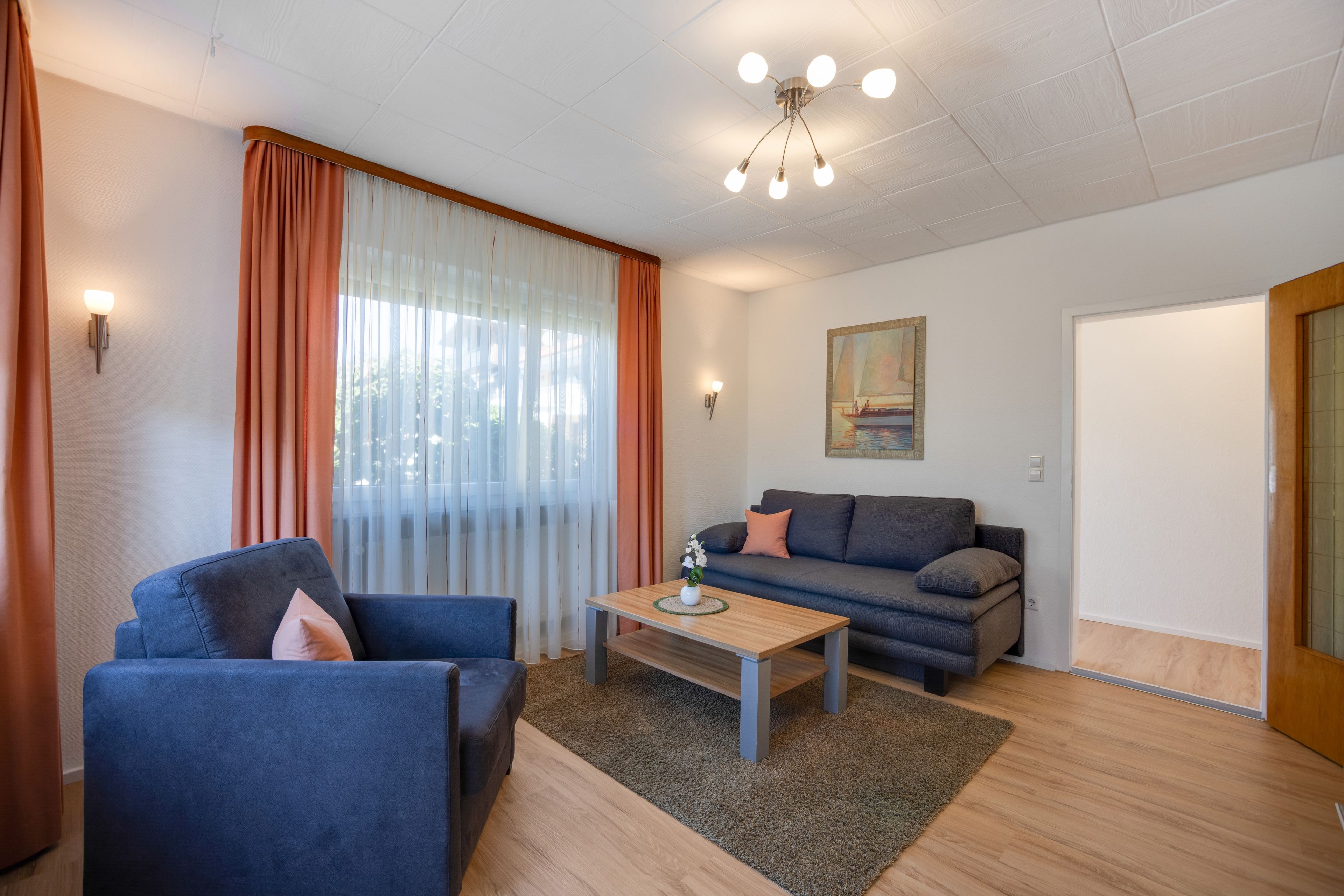 Ein modernes Wohnzimmer mit einer Couch, einem Couchtisch und einem Bild an der Wand.