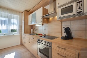 Een moderne keuken met houten kastjes, een oven van roestvrij staal, een magnetron en een koffiezetapparaat.