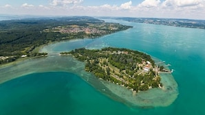 An aerial view of a coastal area with a small island featuring dense greenery and a few buildings.