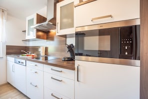 Een moderne keuken met roestvrijstalen apparatuur, houten kastjes en een inbouwoven.