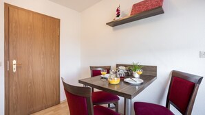 Un comedor con una mesa de madera, sillas tapizadas en rojo y un estante pequeño arriba.