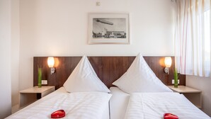 Una habitación de hotel con dos camas, un cuadro en la pared y lámparas de noche.