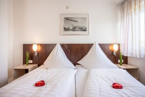 Een hotelkamer met twee bedden, een ingelijst schilderij aan de muur en bedlampjes.