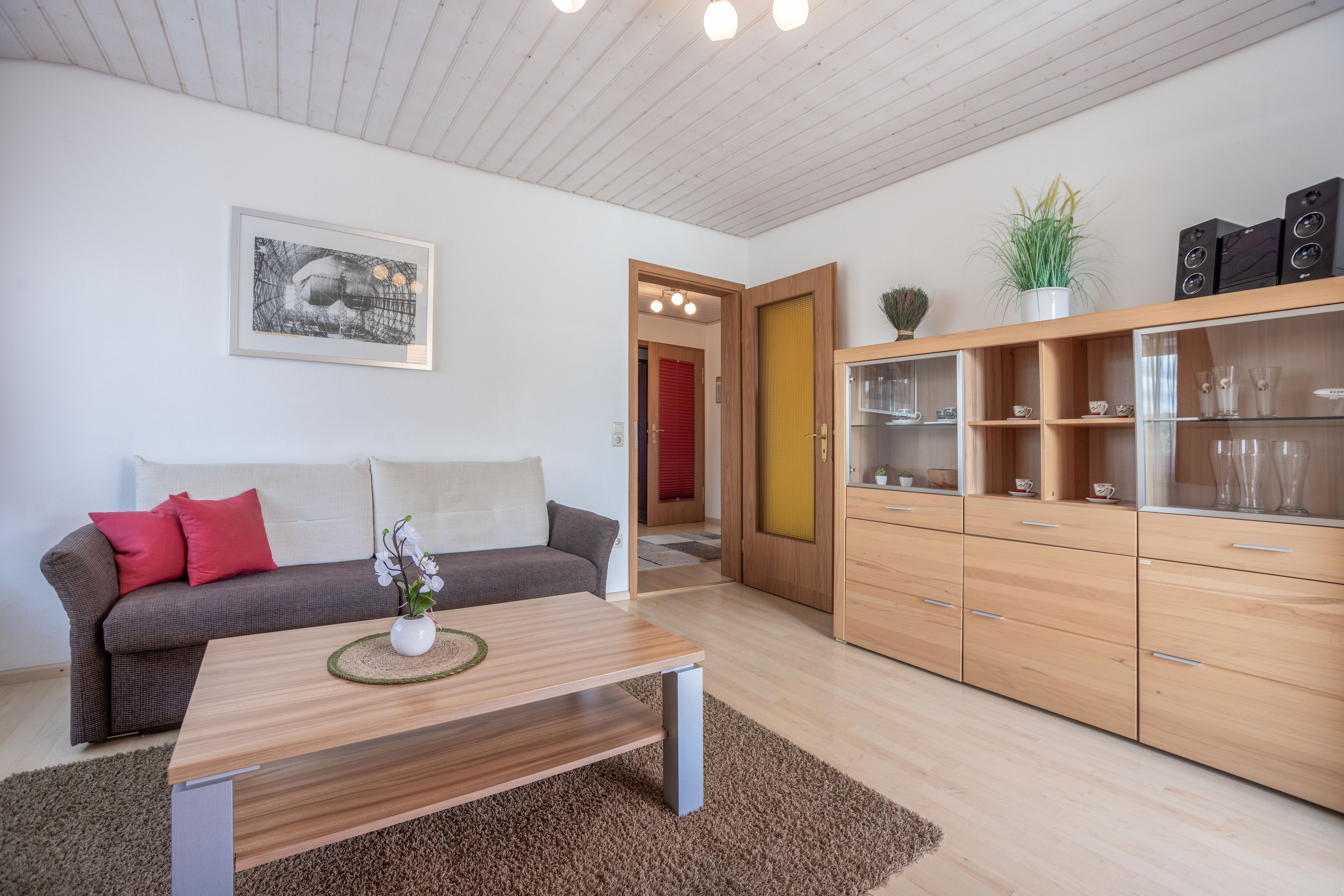 A modern living room with a sofa, coffee table, and wooden cabinets.