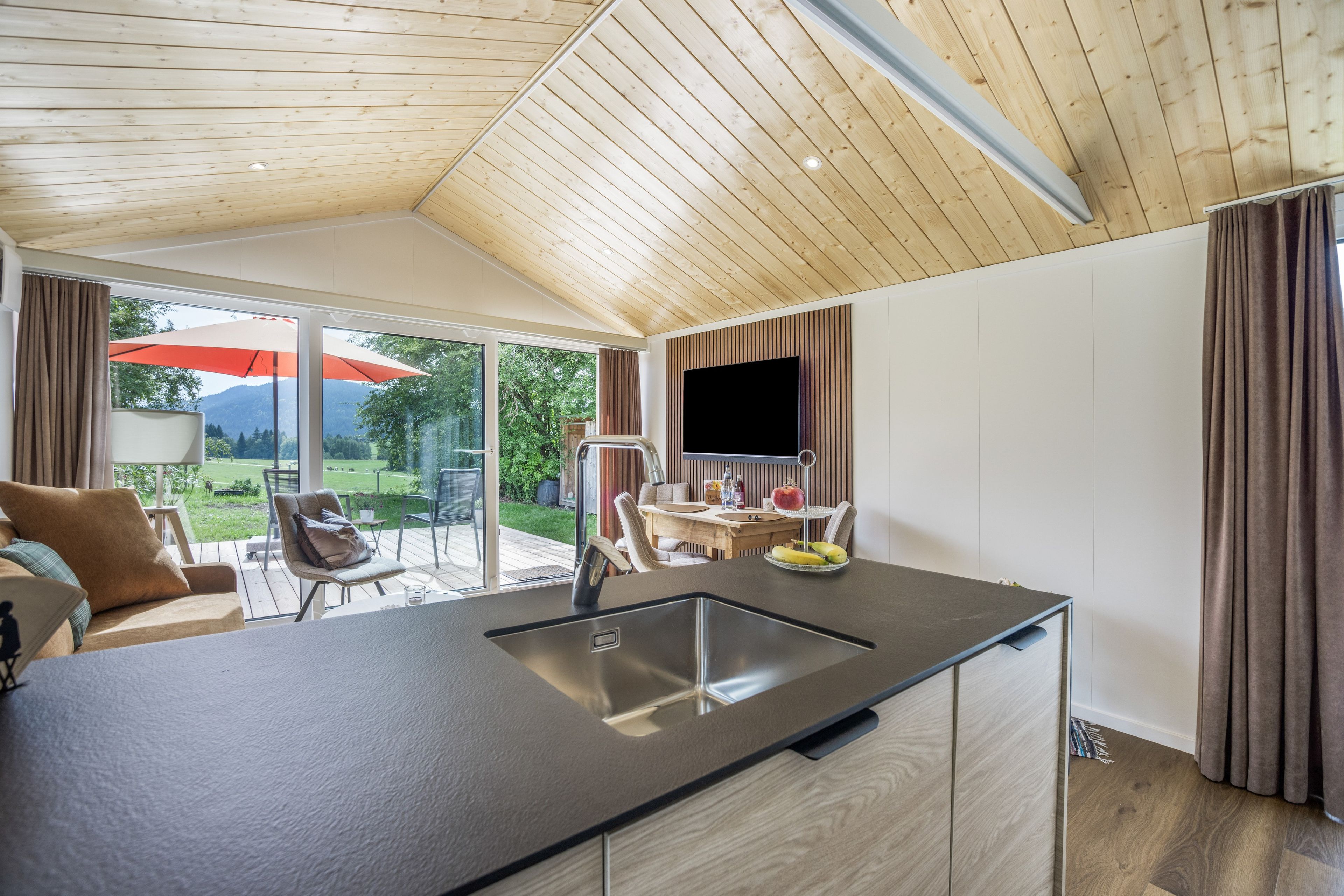 Eine moderne Küche mit einer großen Kochinsel, einem Essbereich mit Tisch und Stühlen sowie einem an der Wand befestigten Fernseher.