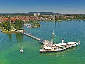 Ein Fluss mit einer Anlegestelle, einem großen Boot und einer kleinen Insel mit Gebäuden.