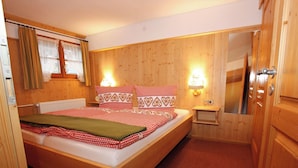 Ein Schlafzimmer mit Holzwänden, einem Bett, Nachttischlampen und einem Spiegel.