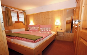 Ein Schlafzimmer mit Holzwänden, einem Bett, Nachttischlampen und einem Spiegel.