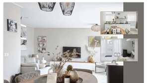 A modern living room with a dining area, featuring a wooden table, a sofa, and a TV. There are decorative items on the table and a bookshelf in the background.