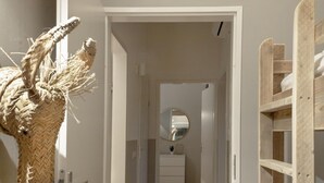 A hallway with a woven basket sculpture, a mirror, and a wooden ladder.