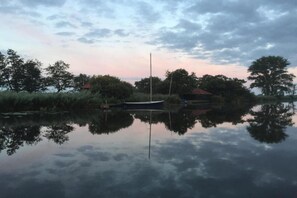 A calm lake with a boat and a small house on the shore. - Apartment in Friesland with Waterfront Views (Offingawier)