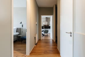 Un pasillo estrecho con suelo de madera que conduce a una cocina moderna.