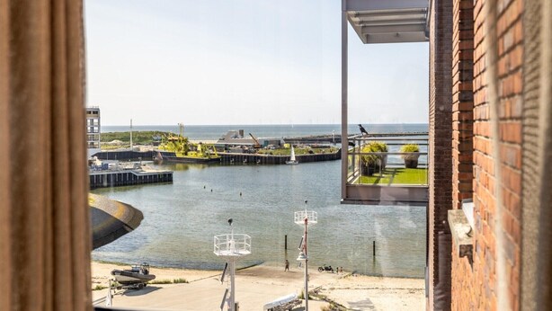 A view of a waterfront area with a dock, boats, and a building with a glass door. - Harbor Retreat, Scheveningen (Scheveningen)