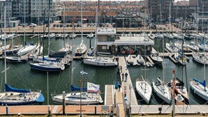 A marina with numerous boats docked, a small building labeled 'Jachtclub Scheveningen', and a row of residential buildings in the background. - Harbor Retreat, Scheveningen (Scheveningen)