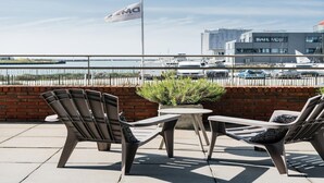 Espace extérieur aménagé avec vue sur un port de plaisance et un bâtiment portant l’inscription « Sail Mon ».