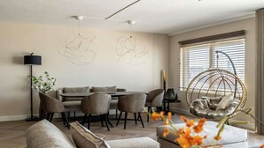 Un salon moderne comprenant un coin repas, un fauteuil suspendu et des œuvres d’art abstraites accrochées au mur.