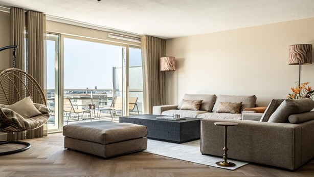 Un salon moderne avec un canapé, un pouf et un fauteuil suspendu.