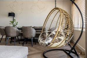 Ett rum med en hängstol, ett matbord, stolar och en lampa.