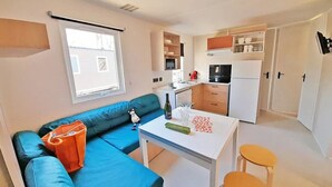 A compact living space with a kitchenette, a sofa, a small dining table, and a window.