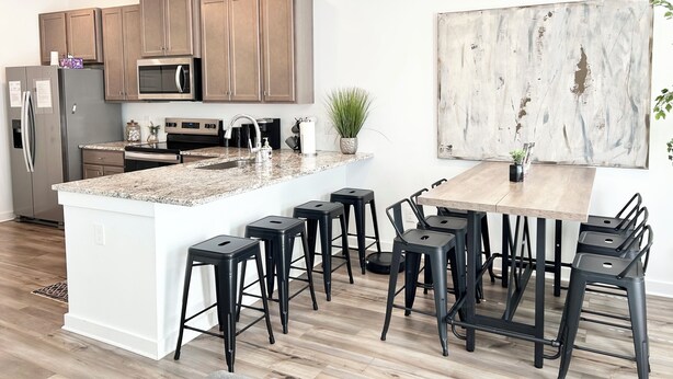 A modern kitchen with granite countertops, stainless steel appliances, and a large island with bar stools.