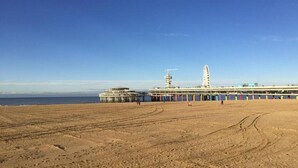 A beach with a pier extending into the ocean, featuring a tall structure and a smaller building. - Sustainable Stay with Terrace (Den Haag)