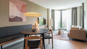 A modern living room with a round table, two chairs, a sofa, and a TV.