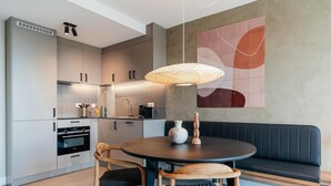 A modern kitchen with a round dining table, a bench, and a pendant light.