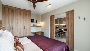 A bedroom with a large bed, wooden wardrobe, and a ceiling fan.