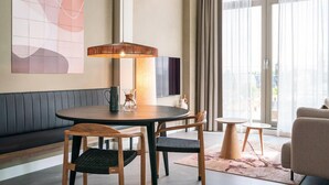 A modern room with a round table, chairs, a sofa, a lamp, and a large abstract painting on the wall.