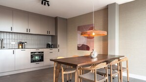 Una cocina moderna con armarios blancos, una mesa de comedor de madera y una lámpara colgante.